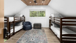 A bedroom with two bunk beds, a ceiling fan, a window, and a patterned rug. - Creek Home, Game Room, Pool Table, AC, EV Chgr, Lake Rights (Lake Arrowhead)