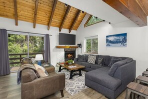 A modern living room with a fireplace, large windows, and a cozy seating area.