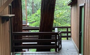 Une terrasse en bois avec une rambarde, entourée d’arbres.