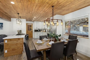 Een moderne keuken met witte kasten, een houten eiland en een eethoek met een tafel gedekt voor vier personen.