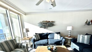 A living room with a blue sofa, striped armchair, and a wooden coffee table. - MVG 1112 3 Bedroom 3 Bath Oceanfront (North Myrtle Beach)