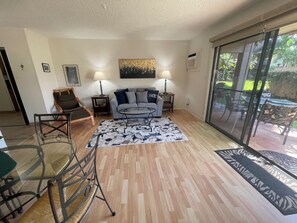 A living room with a sofa, two side tables with lamps, a glass coffee table, and a patterned rug.