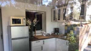 A compact kitchen with a refrigerator, microwave, and a coffee maker on the counter. - Mas des Micocouliers (Montagnac)
