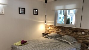 A neatly made bed with a polka dot bedspread, two pillows, and two folded towels. - Mas des Micocouliers (Montagnac)