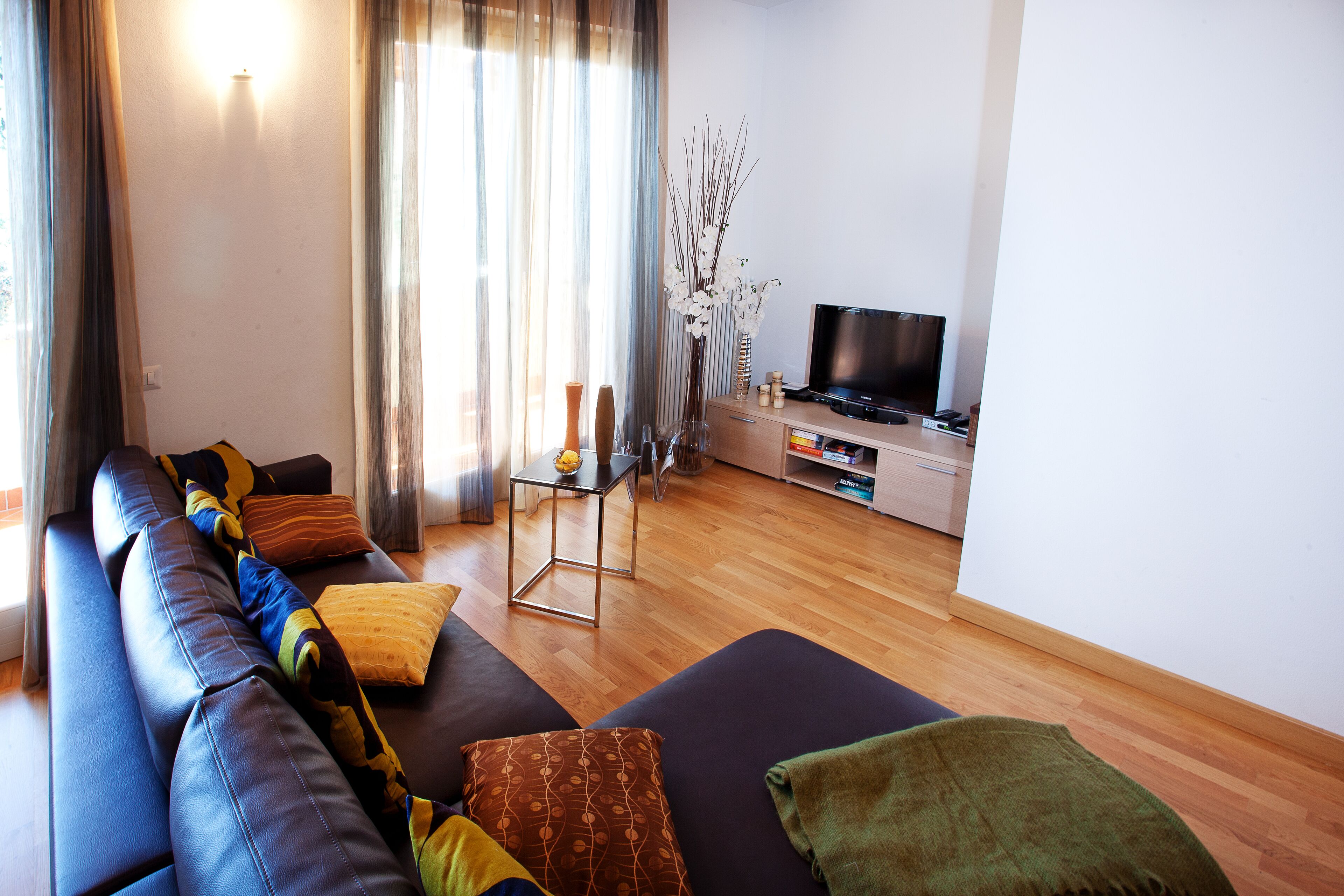 Ein modernes Wohnzimmer mit einer Couch, einem Fernseher und einem kleinen Tisch mit Dekoration.
