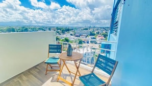 Un balcón con dos sillas y una mesa, con vistas a un paisaje urbano.