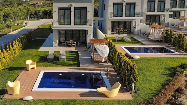 A modern villa with a swimming pool, outdoor seating, and a view of the countryside. - Soleado Luxury Villas (Kassandra)