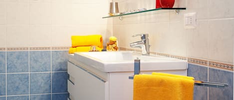 Une salle de bain avec un lavabo blanc, un miroir et une fenêtre.