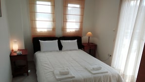 A neatly made bed with white linens, two bedside tables with lamps, and a window with sheer curtains. - Luxury Apartment Thermaikos (Thermaikos)