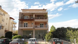 A multi-story residential building with balconies, parked cars, and a clear sky. - Luxury Apartment Thermaikos (Thermaikos)