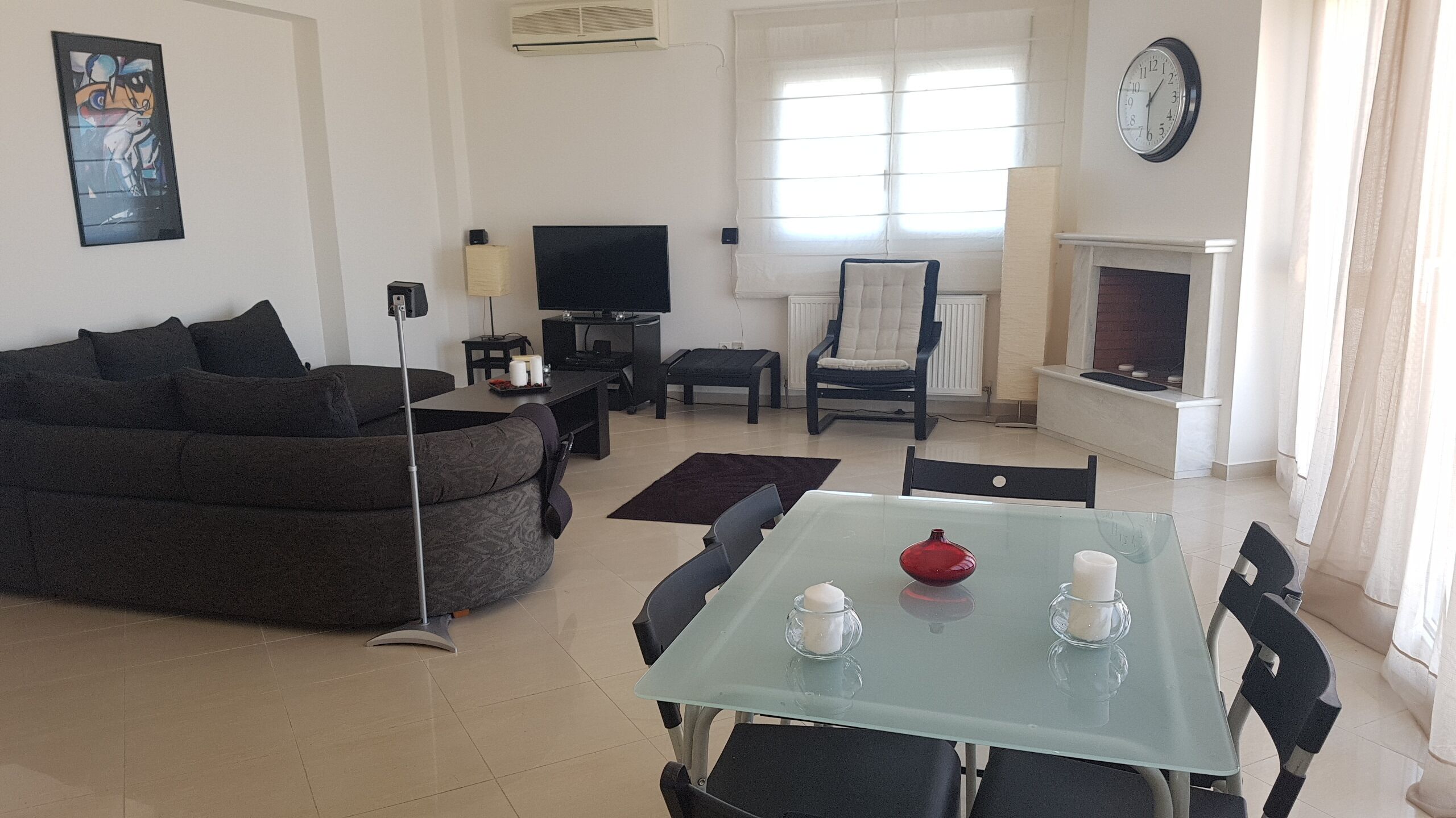 A modern living room with a sofa, TV, fireplace, and dining area with chairs and a table.