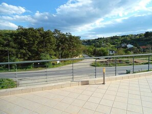A paved walkway with a metal railing, leading to a road with a curve. - Luxury Apartment Thermaikos (Thermaikos)