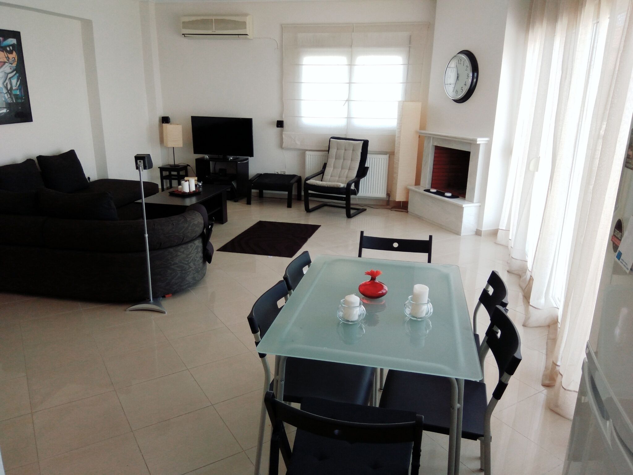 A modern living room with a sofa, TV, fireplace, and dining area with a glass table.