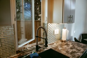 Enjoy a view of the outdoors from the large window in this kitchen, featuring a sink and unique faucet.