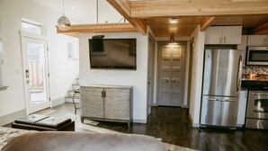 A modern kitchen with stainless steel appliances, a flat-screen TV, and wooden beams.