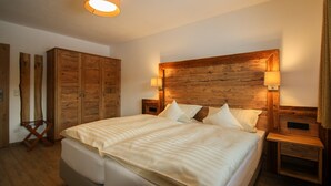 Un dormitorio con una cama grande, cabecera de madera, dos mesitas de noche y un armario.