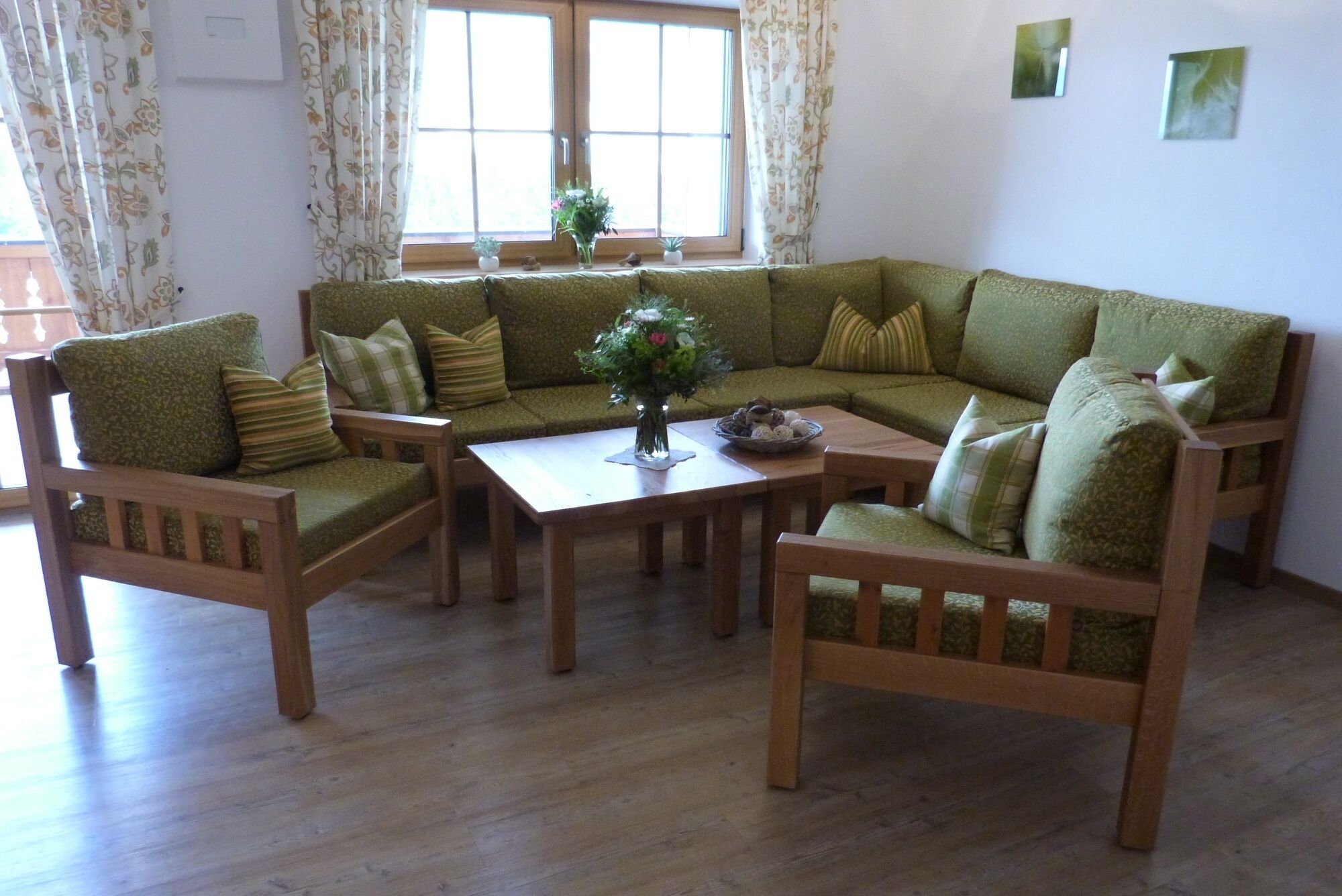 A cozy living room with a green sofa set, wooden chairs, and a coffee table.