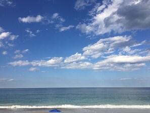 A beach with a clear sky and a few clouds.