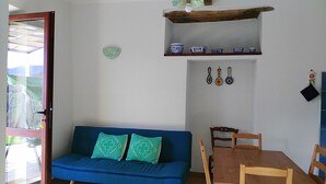 A room with a blue sofa, a wooden dining table, and a shelf with blue and white bowls. - New!Peonia house in the mountains wonderful panorama (Sardinia) Last minute!26Lug-2LtCl (Seulo)