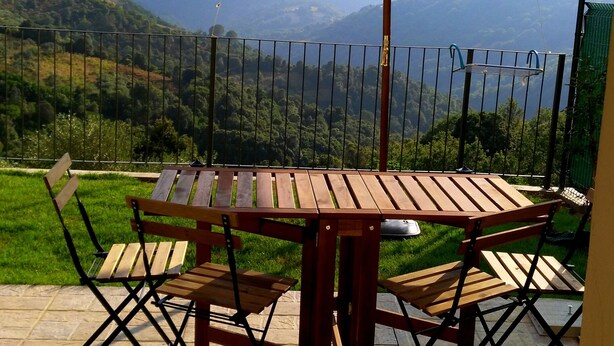 An outdoor patio with a wooden table and chairs, a large umbrella, and a view of rolling hills in the background. - New!Peonia house in the mountains wonderful panorama (Sardinia) Last minute!26Lug-2LtCl (Seulo)