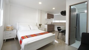 Een moderne hotelkamer met een groot bed, een bureau en een kitchenette.