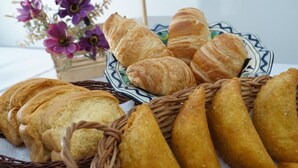 Een tafel met manden vol brood, waaronder croissants en stokbroden.