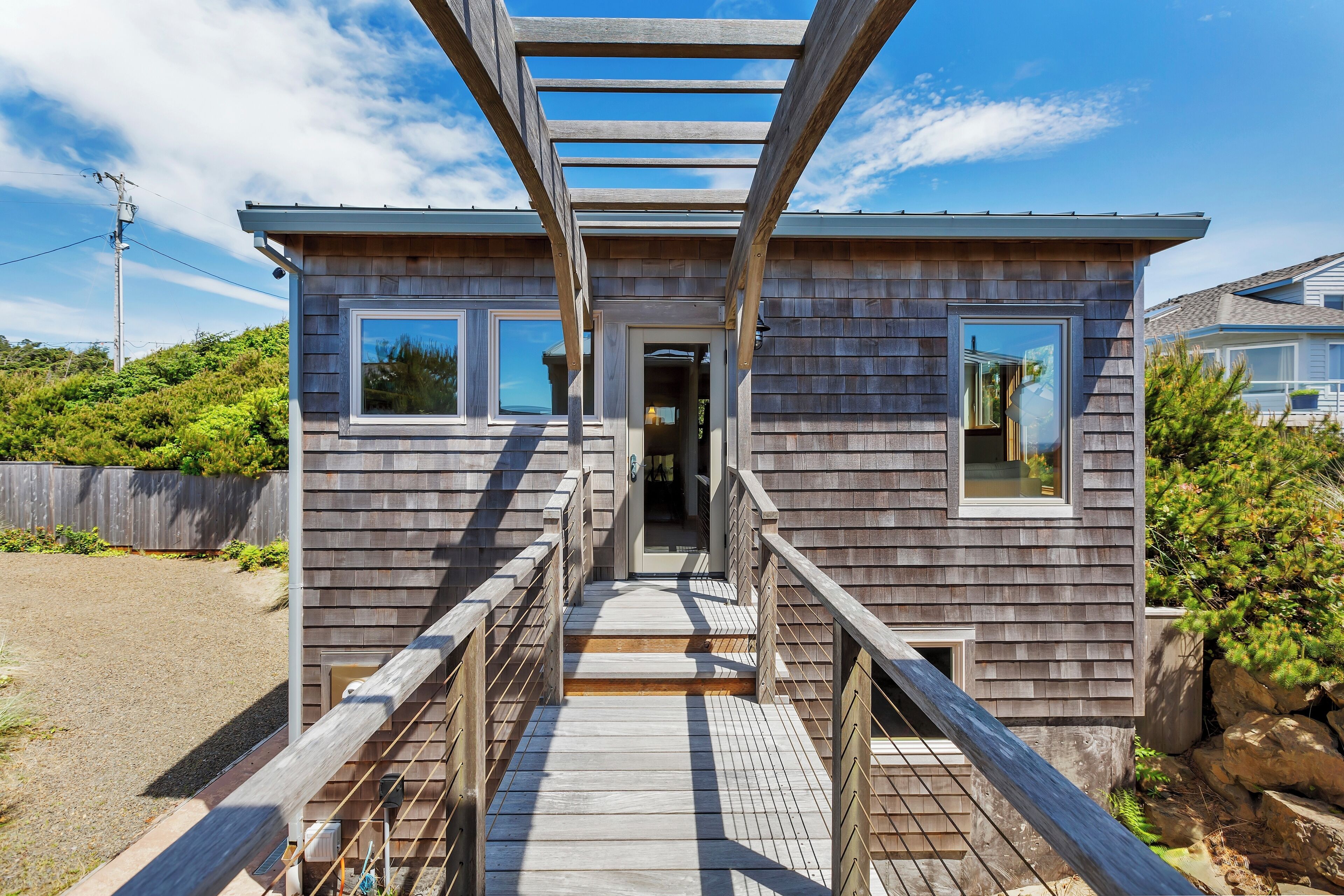A wooden house with a covered porch and a pathway leading to the entrance.