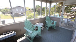A covered porch with two green Adirondack chairs, a small table, and a bench. - In The Heart of Hatteras Village. Close to Beach, Restaurants and Marinas. (Hatteras)