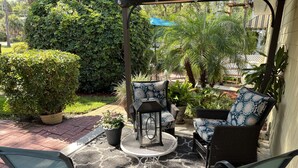 Un patio con mobiliario de mimbre, un farol y plantas en macetas.