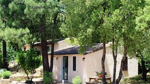 Un petit bâtiment d’un seul étage, doté d’un toit en tuiles, entouré d’arbres et d’un mur de pierres.