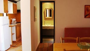 Une cuisine compacte avec des meubles en bois, un réfrigérateur blanc et un coin repas comprenant une table et des chaises en bois.
