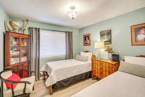 Une chambre avec deux lits, une commode en bois, un globe terrestre et une lampe.