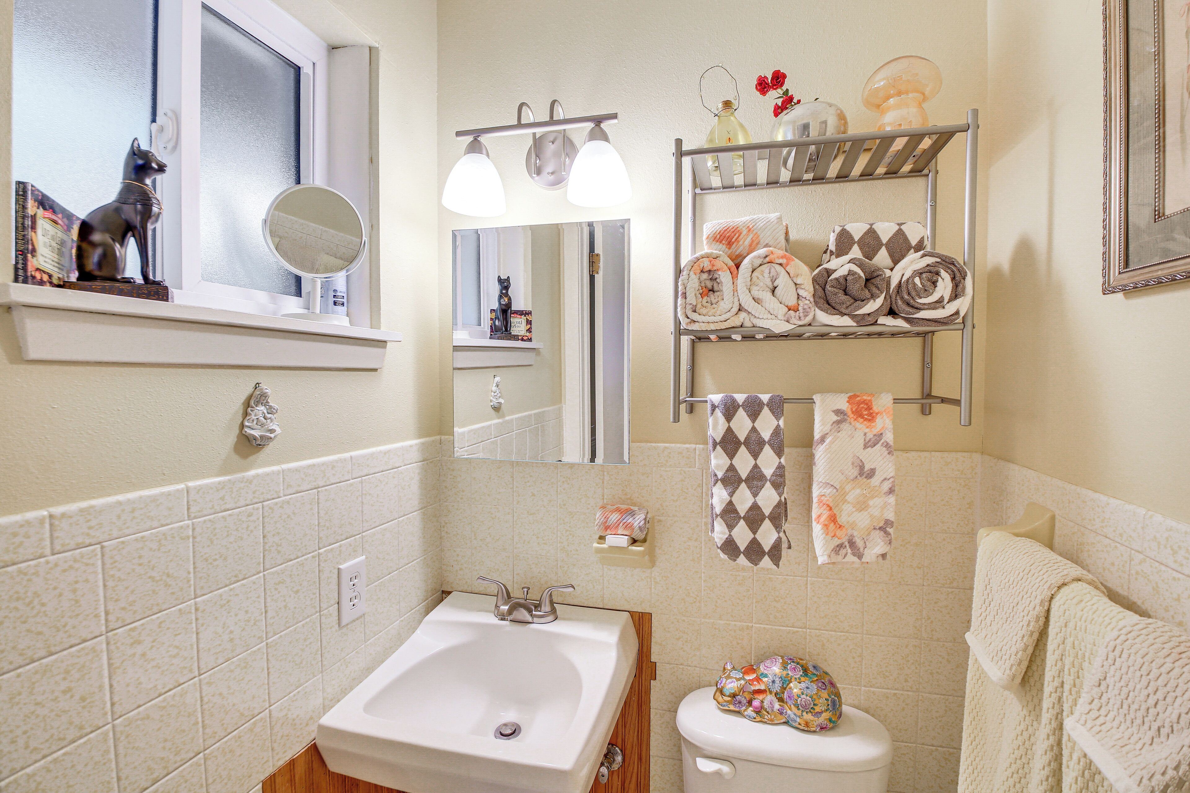 Une salle de bain équipée d’un lavabo, d’un miroir, de toilettes et d’étagères où sont rangées les serviettes.