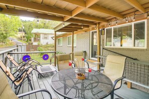 Une terrasse extérieure couverte, avec une table ronde en métal, des chaises et un petit muret en briques.