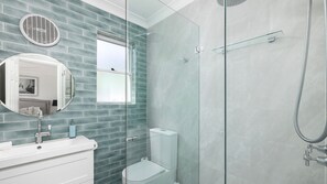 A modern bathroom with a glass shower enclosure, a white toilet, and a vanity with a mirror. - Water Views on Wallawa - Gorgeous Nelson Bay Water Views (Nelson Bay)