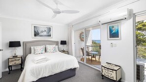 A bedroom with a bed, two bedside tables, a ceiling fan, and a view of the outdoors through a sliding glass door. - Water Views on Wallawa - Gorgeous Nelson Bay Water Views (Nelson Bay)
