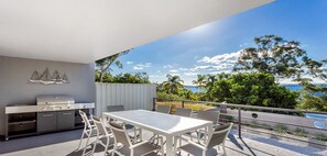A modern outdoor kitchen with a grill, dining table, and chairs. - Water Views on Wallawa - Gorgeous Nelson Bay Water Views (Nelson Bay)