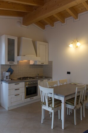 A kitchen with white cabinets, a stove, and a dining table with chairs.
