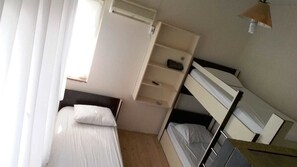 Habitación triple económica | Cortinas blackout, tabla de planchar con plancha y ropa de cama