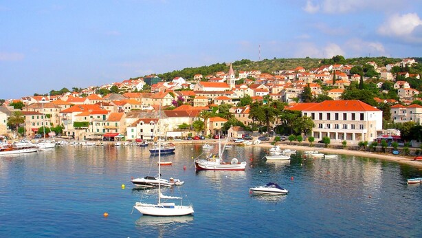 A coastal town with a marina filled with boats, surrounded by buildings with red roofs. - Beachfront apt. with big terrace &  garden (Postira)