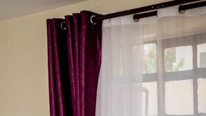 A window with a purple curtain and sheer white curtains partially drawn. - Lomu Homes Kilimani (Nairobi)