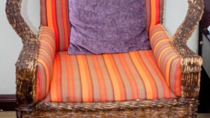 A wicker chair with a striped cushion and a purple pillow. - Lomu Homes Kilimani (Nairobi)