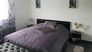Ein Schlafzimmer mit einem Bett, zwei an der Wand befestigten Bildern, einem Nachttisch und einem Dekorationsgegenstand.