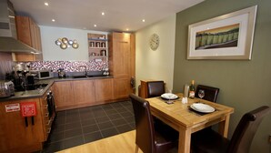 A modern kitchen with wooden cabinets, a tiled backsplash, and a dining area with a wooden table and chairs. - City Centre Skeldergate 1 Bed Apartment With Parking (York)