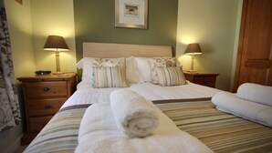 A neatly made bed with a striped bedspread, two bedside tables with lamps, a wooden nightstand, and a framed picture on the wall. - City Centre Skeldergate 1 Bed Apartment With Parking (York)
