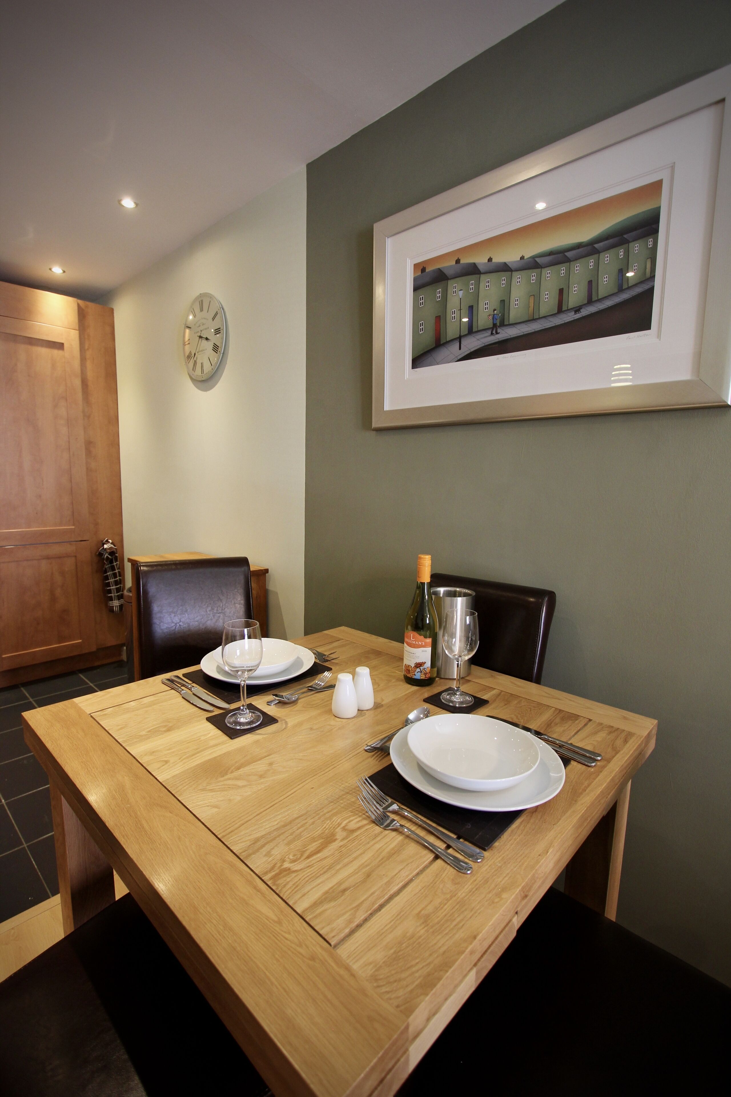 A dining table set with plates, cutlery, and a bottle of wine.