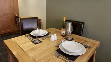 A dining table set with plates, cutlery, and a bottle of wine.