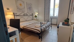 Un dormitorio con cama, mesita de noche, lámpara y ventana con cortinas.