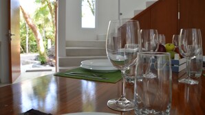 Une table à manger avec plusieurs verres à vin et des assiettes, un set de table vert et une boîte de pommes.