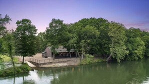 A lakeside cabin with a dock, surrounded by dense trees and a clear sky.